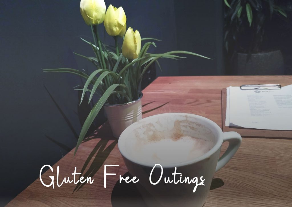 Gluten free outings - cup of coffee, menu and yellow tulips on a table