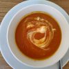 Carrot and sweet potatoe soup served in a bowl with sour cream swirl