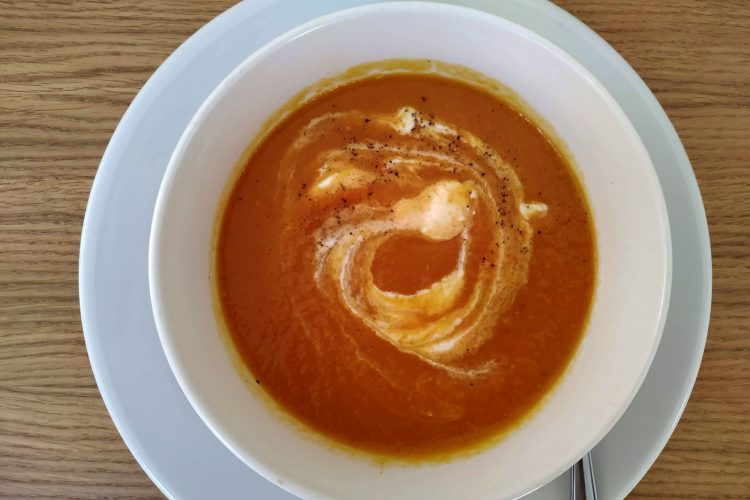 Carrot and sweet potatoe soup served in a bowl with sour cream swirl