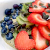 Green smoothie bowl with blueberries, strawberries and kiwis close up