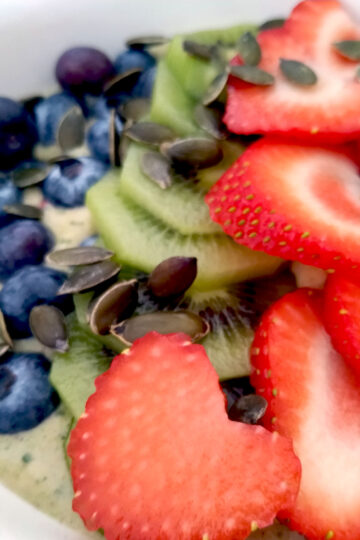 Green smoothie bowl with blueberries, strawberries and kiwis close up