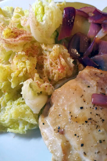 Pan fried lemon chicken on a plate with boiled baby potatoes and steamed savoy cabbage