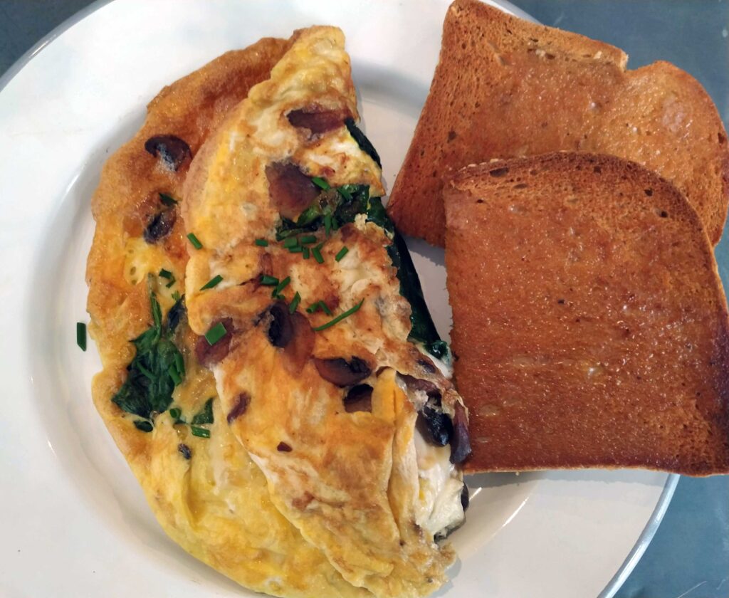 Omelette served on a white plate with buttered gluten-free bread slices