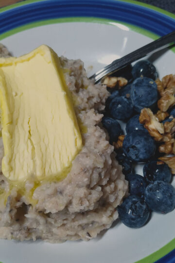 Buckwheat porridge in a bowl with butter, blueberries and walnuts