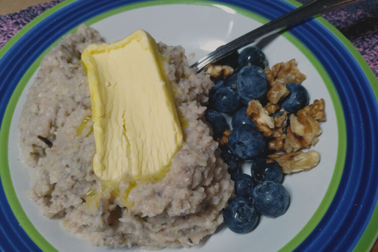 Buckwheat porridge in a bowl with butter, blueberries and walnuts